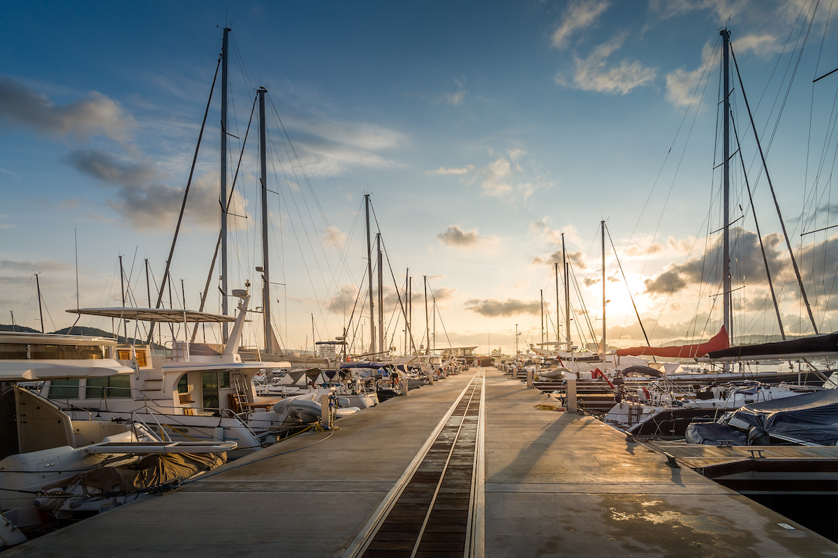 Boats lined up at a marina while the sun is setting. 